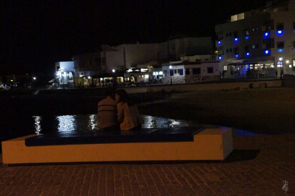 Couple sitting on a bench at night at the harbour in Corralejo