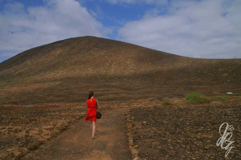 Landscape at the Isla de Lobos with a girl in a red dress walking along the path